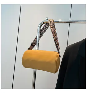 Dettaglio borsa a cilindro giallo zenzero con tracolla leopardata e ganci in argento