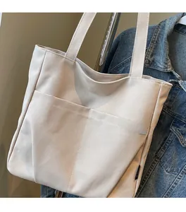 Detail of minimalist beige canvas tote bag with MIDOL lettering and spacious front pocket