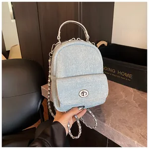 Detail of light blue denim mini handbag featuring silver chain strap and metal turn-lock