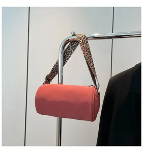 Dettaglio borsa cilindrica rosso corallo con ampia tracolla a stampa leopardata
