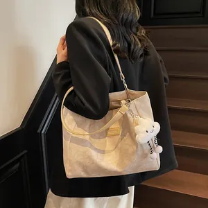 Chic beige embossed tote bag with cloud charm shown on model in urban setting