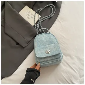 Detail of light blue denim mini backpack featuring silver twist lock and chain strap