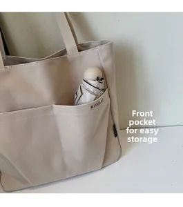 Detail of beige canvas tote bag showing front pockets for easy umbrella storage
