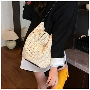 Detail of hand-woven cream bucket bag featuring a brown leather base and slim strap