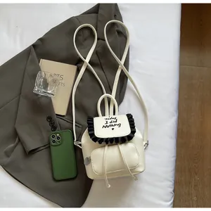 Dettaglio mini zaino bianco con bordo a volant nero e ricamo con scritta a cuore