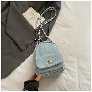 Close-up of light blue denim mini backpack with metal twist lock and chain strap