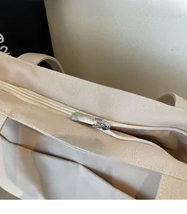 Detailed close-up of smooth silver metal zipper on durable off-white canvas tote bag