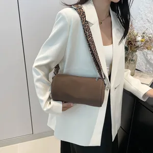 Borsa a cilindro marrone con tracolla leopardata indossata su blazer bianco da modella