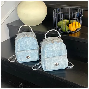 Close-up of mini denim backpacks with chain straps and silver twist-lock hardware detail