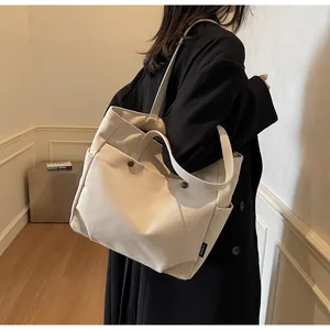 Detail of off-white canvas tote bag with dual straps and side pocket on black blazer