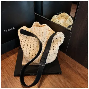 Detailed macro view of cream straw bucket bag with black leather strap and metal buckle