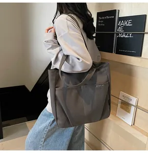 Detail view of charcoal canvas tote bag featuring large outer pocket and durable shoulder strap