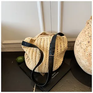 Detail of hollow-out woven straw bucket bag with adjustable black leather strap