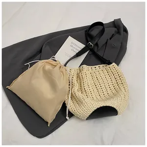 Detail of woven straw bucket bag with black leather shoulder strap and drawstring liner