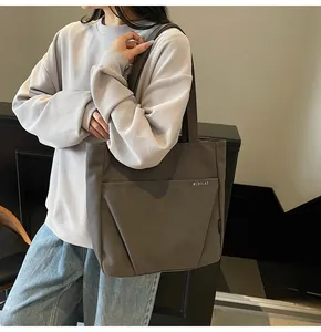 Close-up of dark grey tote bag with MIDOLAI lettering worn by a model in casual wear