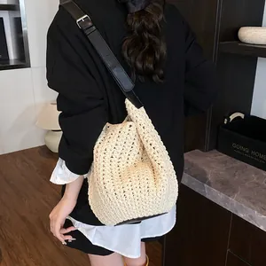 Chic woven beach bucket bag with black leather strap shown on model in summer setting