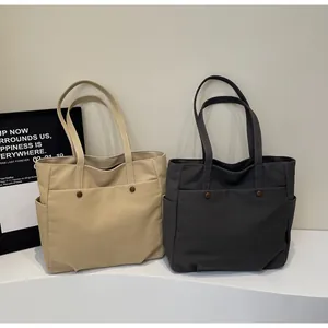 Detail of khaki and dark grey canvas tote bags with front button pockets and side pockets