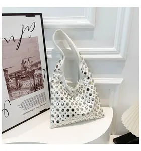 Detail view of white leather shoulder bag featuring stylish silver rivet decorations