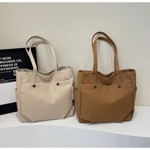 Detailed view of canvas tote bags in cream and brown with functional exterior pockets