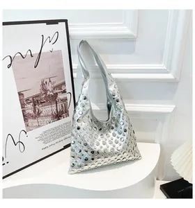 Detailed view of silver Hobo bag with metallic rivets on a minimalist white stand