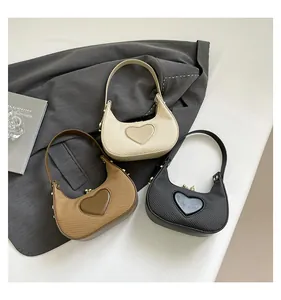 Drei halbmondförmige Taschen in Beige, Braun und Schwarz mit Herz-Prägung und Lederstruktur