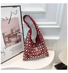 Detailed view of deep red leather shoulder bag featuring silver studded punk accents