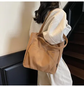 Close-up of the spacious outer pocket and durable canvas texture on a tan tote bag