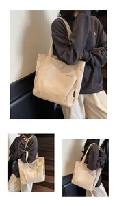 Detailed close-up of a cream canvas tote bag showing the front pocket and brand logo