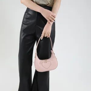 Rosa sichelförmige Hobo-Tasche mit Herzprägung und goldener Hardware am Model