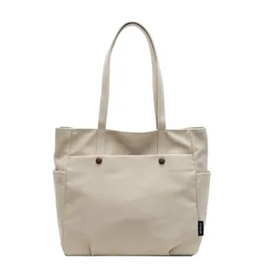Minimalist beige canvas tote bag with large capacity pockets and durable shoulder straps