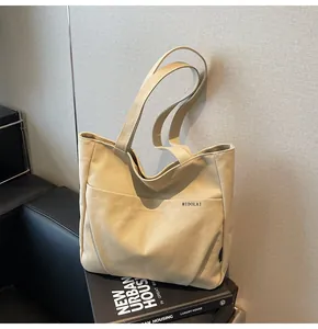 Close-up of beige canvas tote bag with front pocket and thick handle on minimalist background
