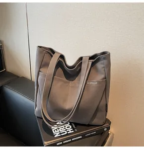 Detailed close-up of heavy-duty canvas tote bag with front pockets on a leather seat