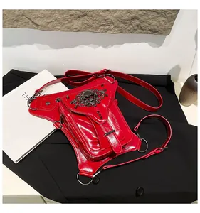 Détail du sac banane en cuir verni rouge avec crâne métallique et rivets punk gothiques