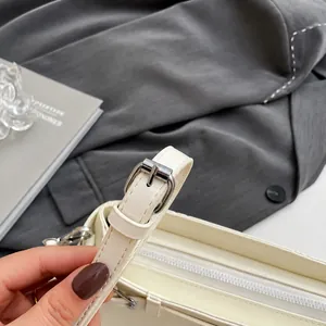 Detail eines verstellbaren Lederriemens mit silberner Schnalle an einer beigen Handtasche