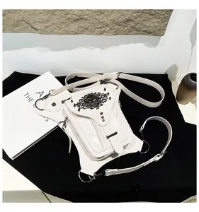 Vue détaillée du sac banane punk blanc avec emblème tête de mort et clous en métal