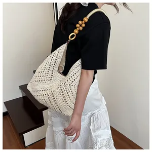 Detail of hand-woven hollow knit bag with decorative wooden beads and metal ring strap