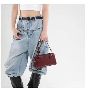 Dunkelrote Leder-Schultertasche mit silbernen Schnallen getragen von einem Model