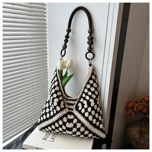 Detail of crochet tote bag with black and white checkerboard pattern and wooden bead handle