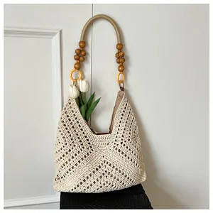 Detail of beige crochet shoulder bag featuring wood beads and yellow link hardware