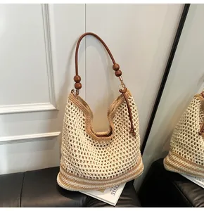 Detail of woven tote bag with crochet texture, brown leather strap, and wooden beads