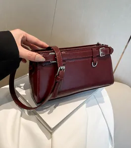 Detail der weinroten glänzenden Kunstleder-Schultertasche mit Schnalle und Reißverschluss