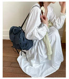 Détail du sac à dos en toile à carreaux avec bretelles noires porté par un mannequin