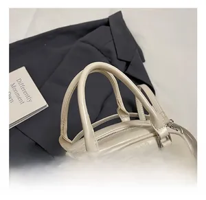 Detailed view of cream PU leather handbag with sturdy handle and secure zipper closure