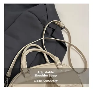 Detail of adjustable shoulder strap and glossy texture on beige multi-pocket pillow bag