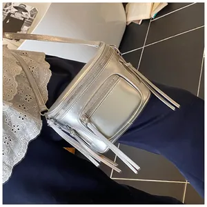 Vue détaillée d'un sac besace argenté avec plusieurs zips à lanières et fini métallisé