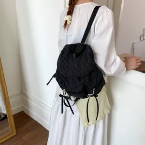 Sac à dos à carreaux noirs avec nœud en ruban, présenté porté de dos pour femme