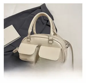 Detail view of off-white retro pillow bag with functional dual front pockets and top handle