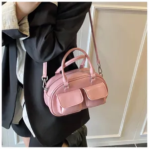 Pink patent leather baguette bag with dual front pockets and adjustable strap on a model