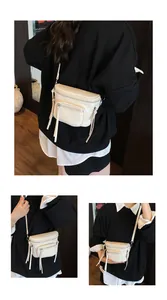 Détails du sac selle minimaliste avec fermetures éclair et tirettes à pompons en cuir crème