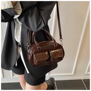 Detailed view of deep brown Boston bag with double front pockets on female model